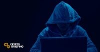 Hacker en una sudadera oscura trabajando en una laptop, sugiriendo un potencial ciberdelito o violación de seguridad relacionada con criptomonedas.