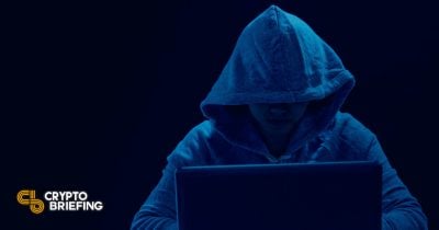 Hacker en una sudadera oscura trabajando en una laptop, sugiriendo un posible crimen cibernético o brecha de seguridad relacionada con criptomoneda.